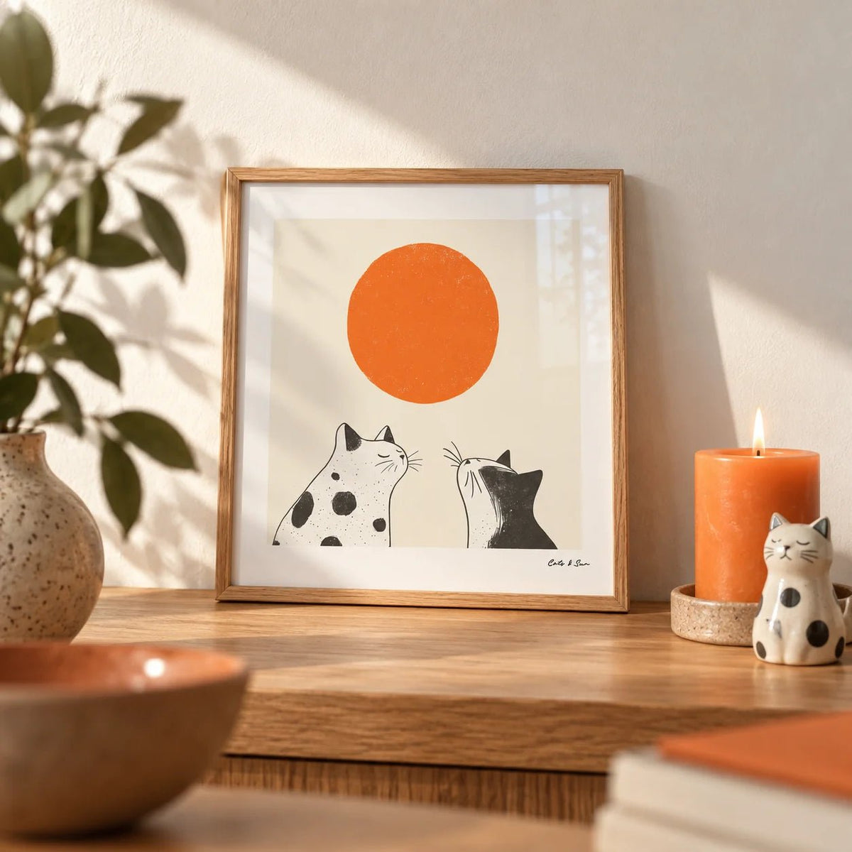 Orange Cat Art, a small A4 framed print leaning on an oak shelf in a living room