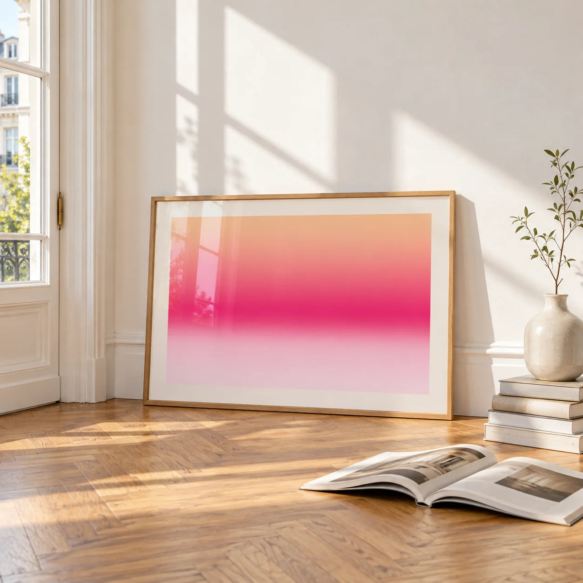 Pink Sunrise Print, framed and leaning on the parquet floor of a bright living room