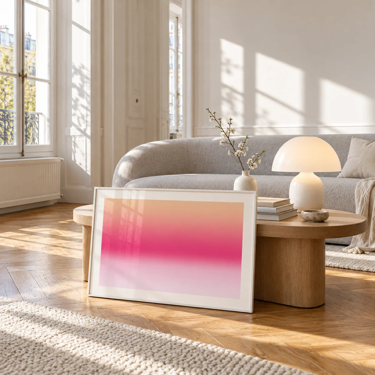 Pink Sunrise Print, framed and leaning against a coffee table in a bright living room