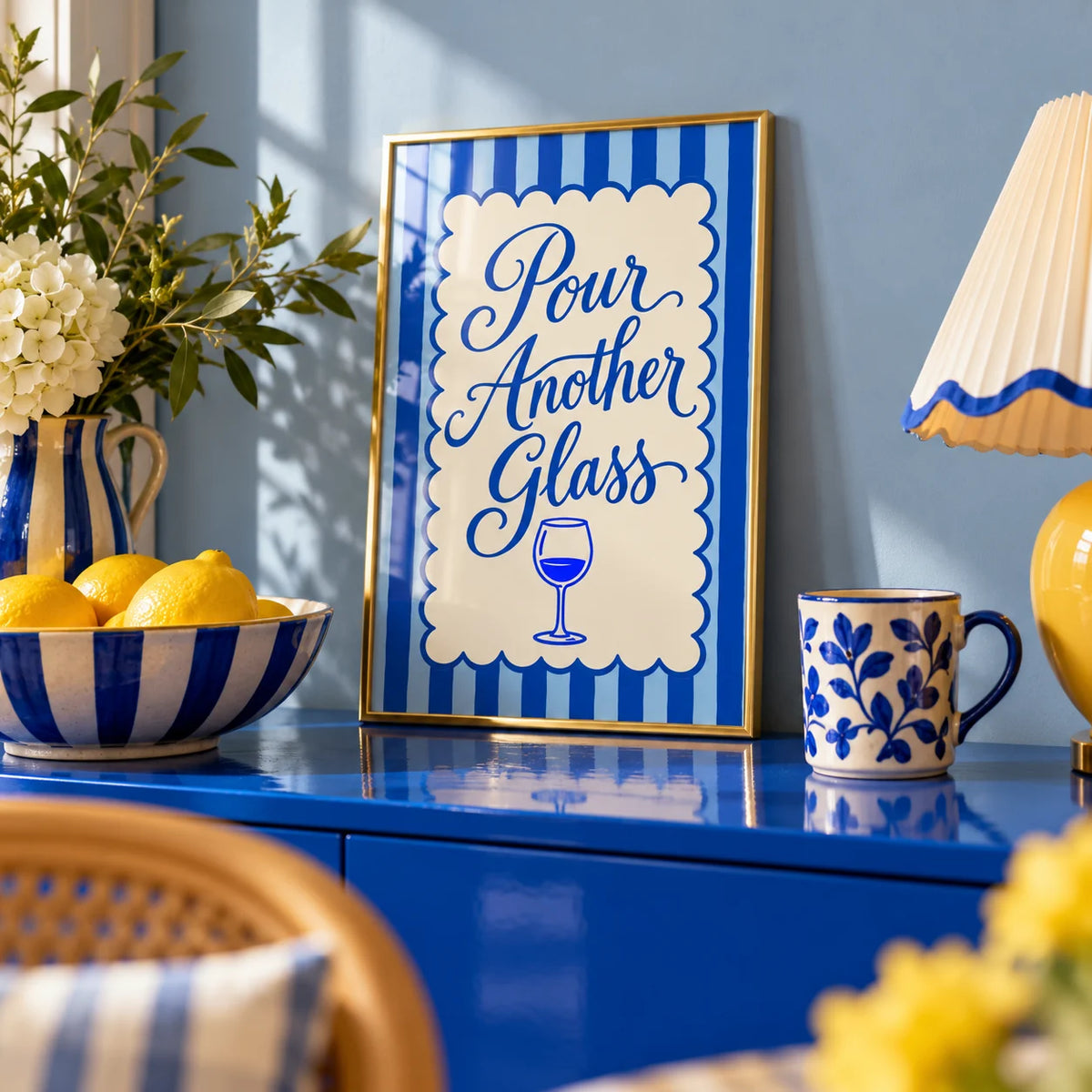 Pour Another Glass Print, a small A4 framed print leaning on a colourful lacquered shelf in a living room