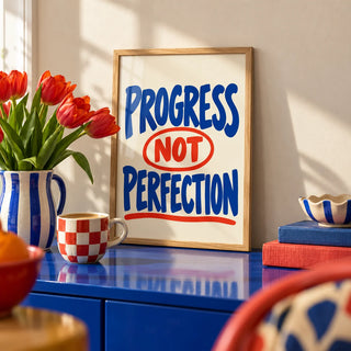 Progress Not Perfection Print, a small A4 framed print leaning on a colourful lacquered shelf in a living room