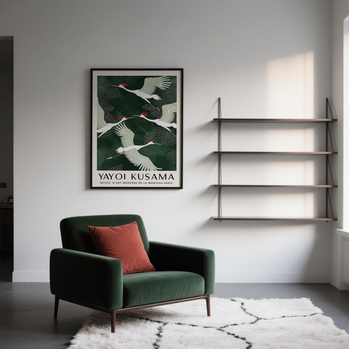 Japandi wall art with white and red cranes flying against a dark green background above a green armchair with a red cushion