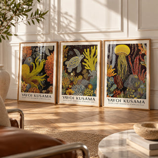 Sea Life Prints Set of 3 styled leaning against a white panelled wall on herringbone parquet: Golden Tentacle, Turtle Drift and Luminous Drift shown framed side by side (frames not included)