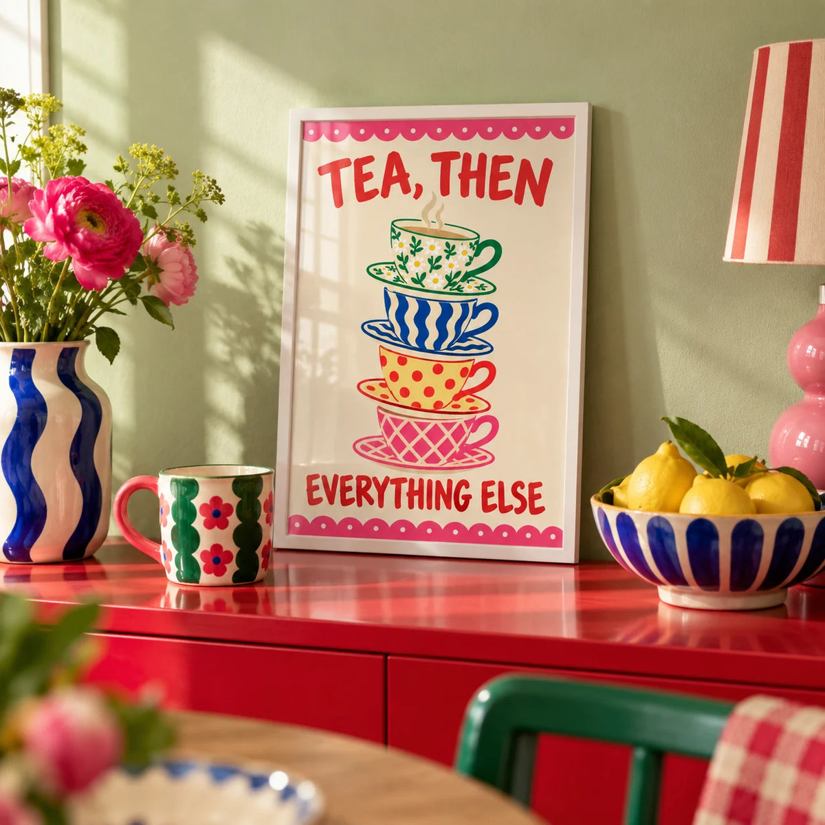Teacup Tower Print, a small A4 framed print leaning on a colourful lacquered shelf in a living room