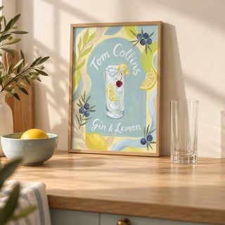 Tom Collins Art Print, a small A4 framed print leaning on a pale oak kitchen worktop