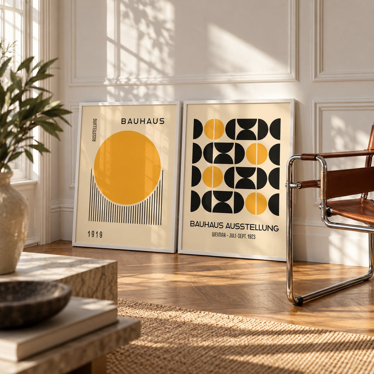 Yellow and Black Bauhaus Prints Set of 2 styled leaning against a white wall beside a chrome and cognac leather sling chair: Golden Dawn and Bauhaus Symmetry shown framed side by side (frames not included)